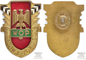 1.Nazwa własna: złota odznaka Wzorowego Żołnierza Wojsk Ochrony Pogranicza
2.Charakterystyka przedmiotu: w centrum orzeł koloru złotego, na czerwonej,emaliowanej tarczy, poniżej, na zielonym tle napis: „WOP”. Po bokach, na złotej wstędze napis: „Wzorowy żołnierz” oraz emaliowane, biało-czerwone słupy graniczne.  Wymiary: 4,6 × 3,3 cm. Nakrętka sygnowana przez Mennicę Państwową
3.Czas powstania: lata 80. XX w.
4.Hasła przedmiotowe: Wojska Ochrony Pogranicza, odznaczenia
5.Miejsce przechowywania/właściciel: Centrum Szkolenia Straży Granicznej w Kętrzynie