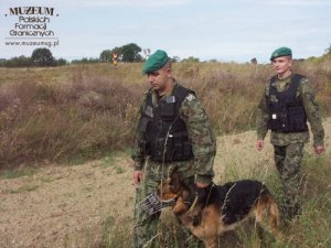 funkcjonariusze Straży Granicznej z psem, patrolujący  strefę nadgraniczną