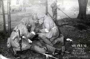 1. Tytuł: ćwiczenia
2. Opis obrazu: żołnierze zespołu medycznego Pomorskiej Brygady Wojsko Ochrony Pogranicza udzielający pierwszej pomocy ofiarom ataku chemicznego
3. Data wydarzenia: 1988 r.
4. Osoby widoczne: brak danych
5. Hasła przedmiotowe: Wojska Ochrony Pogranicza, manewry 
6. Opis techniczny: oryginał, czarnobiałe
7. Autor: brak danych
8. Miejsce przechowywania/właściciel: Archiwum Straży Granicznej w Szczecinie